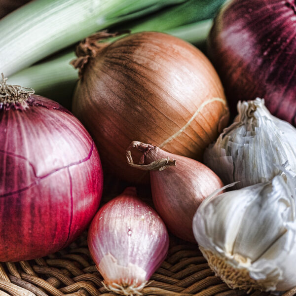 A selection of onions and garlic in a basket