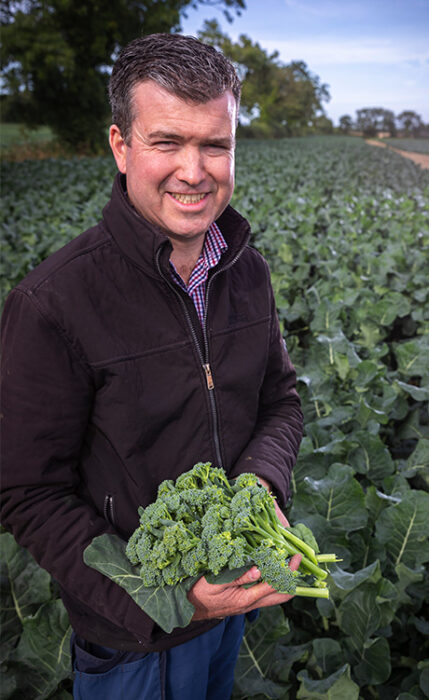 grower in a field holding broccoli