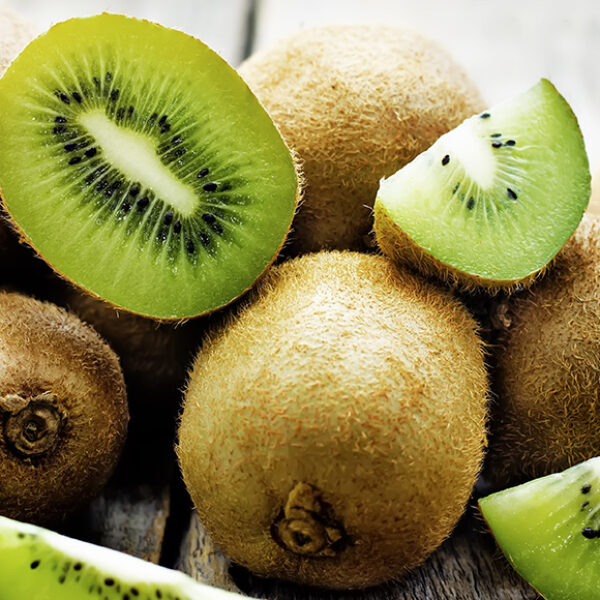 Kiwis on a table top with some sliced in half and quarters