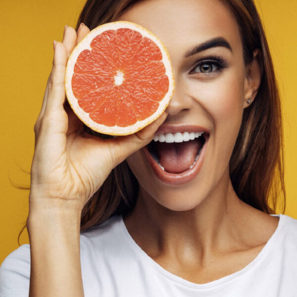 Woman holding half a grapefruit up to her eye